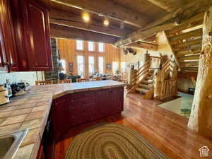 Kitchen featuring a peninsula, tile counters, wood finished floors, and open floor plan