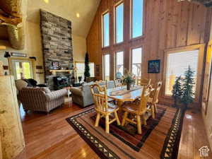 Dining space featuring high vaulted ceiling, a stone fireplace, and wood finished floors