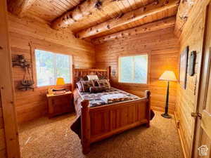 Carpeted bedroom featuring beamed ceiling, wood walls, and wooden ceiling