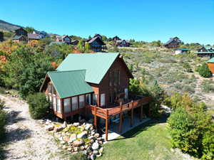 Back of property featuring a wooden deck, a lawn, and metal roof