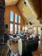 Living room featuring beamed ceiling, wood finished floors, high vaulted ceiling, and a healthy amount of sunlight