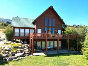 Back of property with a lawn, a patio area, a deck, and metal roof