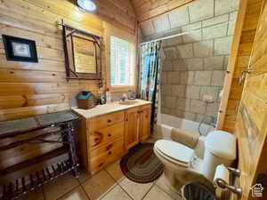 Full bathroom featuring tile patterned floors, toilet, wood walls, shower / bathtub combination with curtain, and vanity