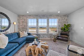 Living area with an accent wall, baseboards, carpet, and a healthy amount of sunlight