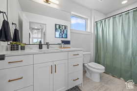 Bathroom featuring toilet, a shower with curtain, and vanity