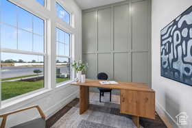 Office with wood finished floors, baseboards, and a decorative wall