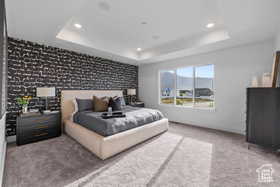 Bedroom with a tray ceiling, an accent wall, carpet floors, and recessed lighting