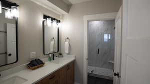 Full bath featuring a marble finish shower, a sink, and double vanity