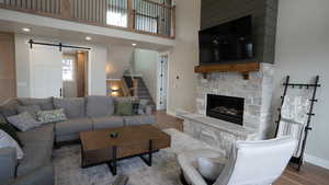 Living area featuring a barn door, wood finished floors, a fireplace, and baseboards