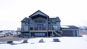 Snow covered rear of property with stairway, a balcony, board and batten siding, french doors, and a garage