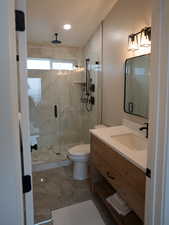 Full bathroom featuring vanity, marble finish floor, a shower stall, and toilet