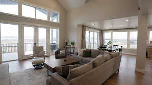 Living room with high vaulted ceiling, baseboards, french doors, and hardwood / wood-style floors