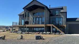 Rear view of house with gravel driveway, stairs, a balcony, and board and batten siding
