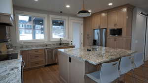 Kitchen featuring stainless steel appliances, a sink, light stone counters, and a kitchen island