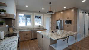 Kitchen featuring a barn door, light stone counters, a center island, open shelves, and stainless steel appliances