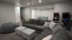 Carpeted living area featuring baseboards, visible vents, recessed lighting, and stairs