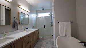 Full bath featuring a freestanding tub, marble finish floor, a stall shower, and a sink