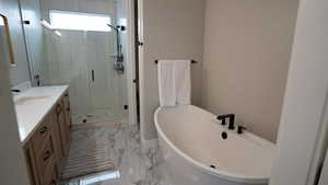 Bathroom featuring a shower stall, a soaking tub, marble finish floor, and vanity
