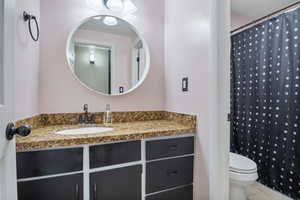 Full bath with a shower with shower curtain, tiled flooring, toilet, and vanity