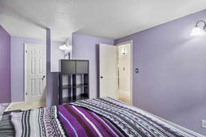 Carpeted bedroom featuring a textured ceiling and baseboards