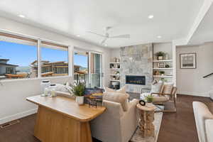 Living area with dark wood-type flooring, a large fireplace, recessed lighting, built in shelves, and a ceiling fan