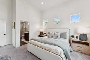 Carpeted bedroom featuring a towering ceiling and ensuite bath