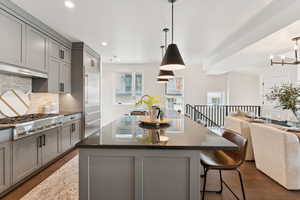 Kitchen with gray cabinets, dark wood-style floors, tasteful backsplash, dark stone counters, and recessed lighting