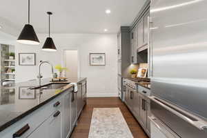 Kitchen with stainless steel appliances, dark stone counters, dark wood finished floors, hanging light fixtures, and recessed lighting