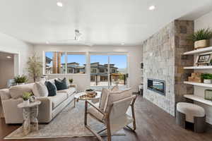 Living room with dark wood-type flooring, a fireplace, and recessed lighting