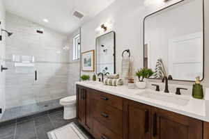 Bathroom featuring double vanity, a shower stall, and tile patterned flooring