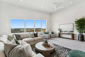 Carpeted living area featuring recessed lighting, a towering ceiling, and a ceiling fan