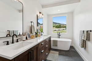 Full bath with double vanity, a freestanding tub, recessed lighting, and a mountain view