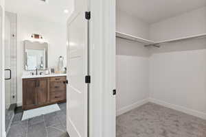 Walk in closet featuring a sink and dark carpet