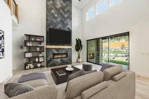 Living room featuring a high ceiling, wood finished floors, a tiled fireplace, and baseboards