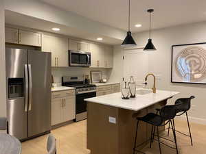 Kitchen with recessed lighting, stainless steel appliances, a sink, a kitchen bar, and light wood-style flooring