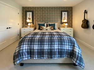 Carpeted bedroom with baseboards and wallpapered walls