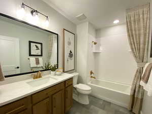 Bathroom featuring shower / bath combination, vanity, and toilet