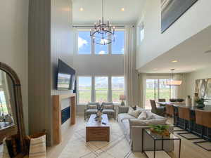 Living area featuring recessed lighting, a tile fireplace, a high ceiling, a chandelier, and light wood-style flooring