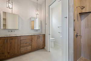 Bathroom with a sink, double vanity, a tile shower, toilet, and tile patterned flooring