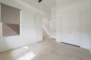 Unfurnished bedroom featuring baseboards, light tile patterned flooring, and a closet