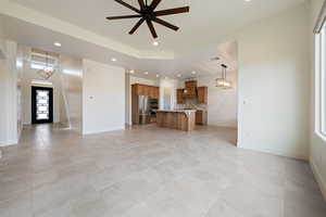 Unfurnished living room with baseboards, recessed lighting, light tile patterned floors, and ceiling fan with notable chandelier