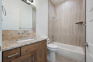 Bathroom featuring decorative backsplash, bathing tub / shower combination, vanity, and toilet