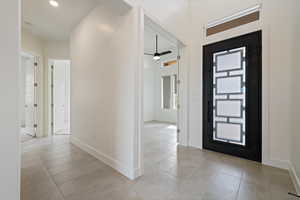 Entryway with ceiling fan, baseboards, and light tile patterned floors