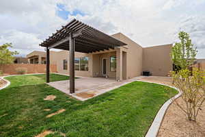 Back of property with a pergola, a lawn, a fenced backyard, and stucco siding
