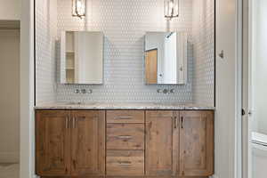 Full bath featuring backsplash, double vanity, toilet, a sink, and baseboards