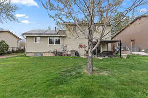 Back of house featuring a lawn, solar panels, and fence private yard