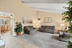 Living room featuring light tile patterned flooring, baseboards, a notable chandelier, beamed ceiling, and high vaulted ceiling