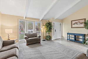Tiled living area featuring vaulted ceiling with beams and baseboards
