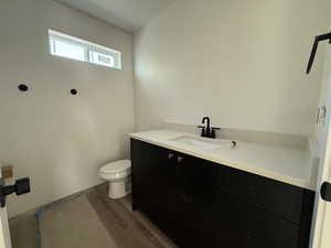 Half bathroom with toilet, wood finished floors, and vanity