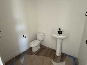 Half bathroom with toilet and wood finished floors